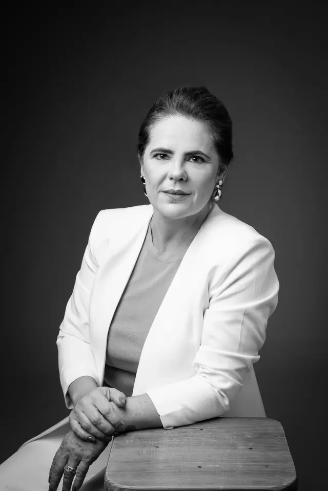 Dra. Michelly Ribeiro, em foto em preto e branco, sentada com as mãos cruzadas